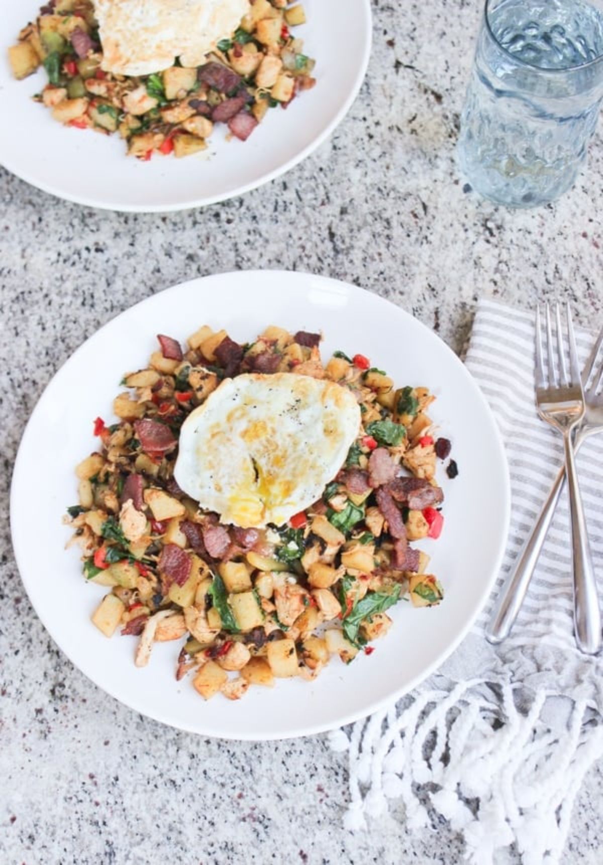 2 white plates of chicken hash topped with a fried egg