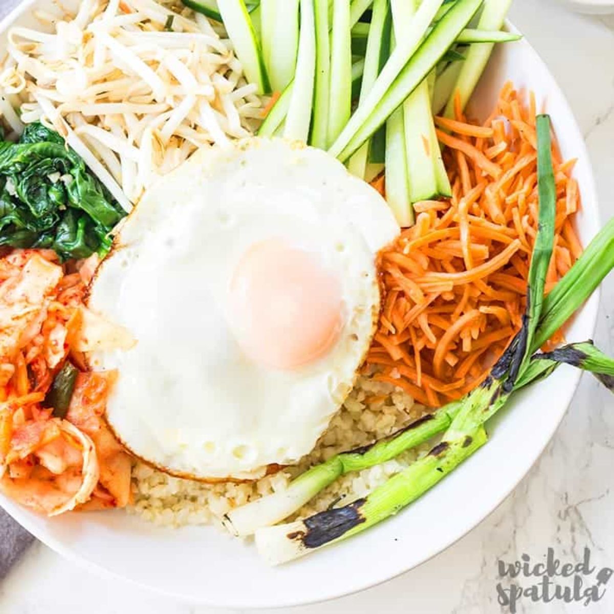 A bowl of korean bibimap with a fried egg on top