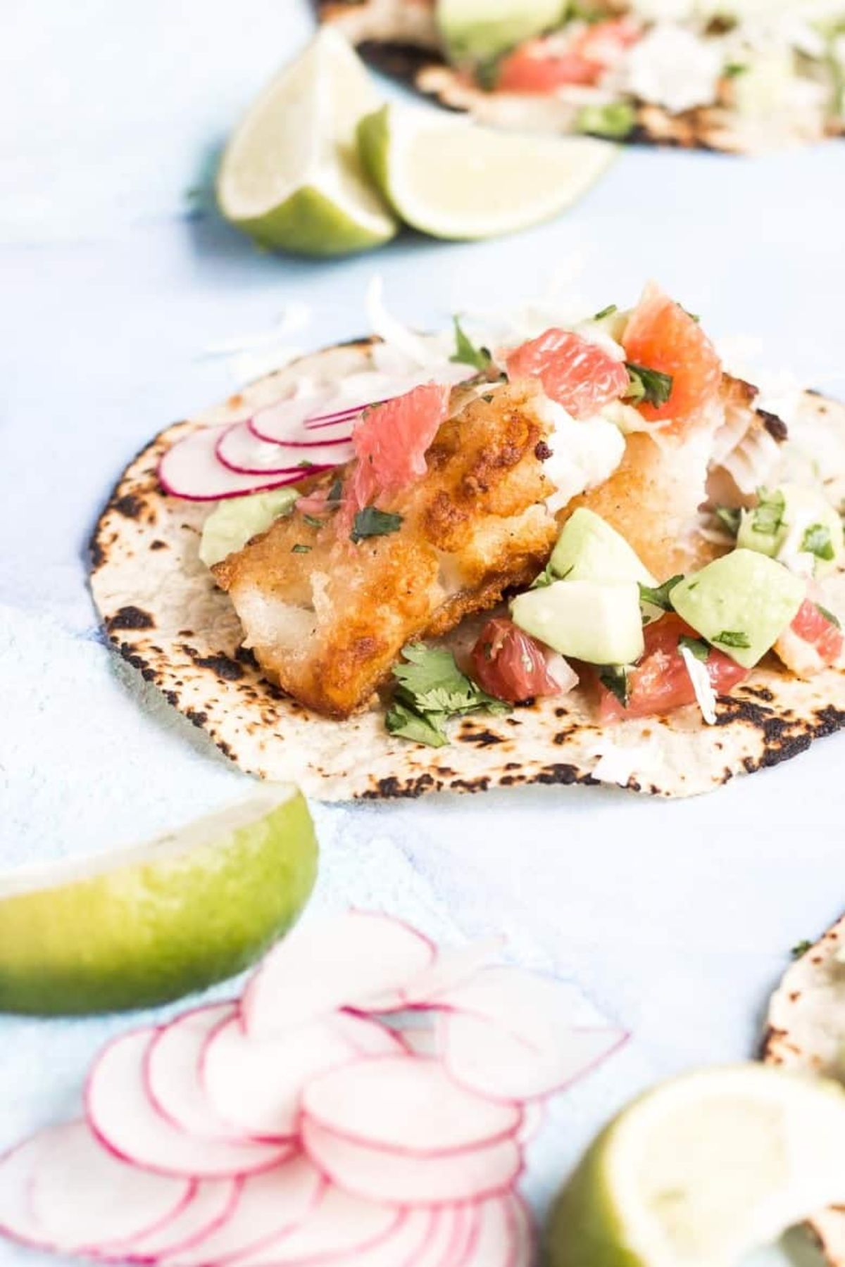 flat tacos topped with battered fish and grapfruit salsa