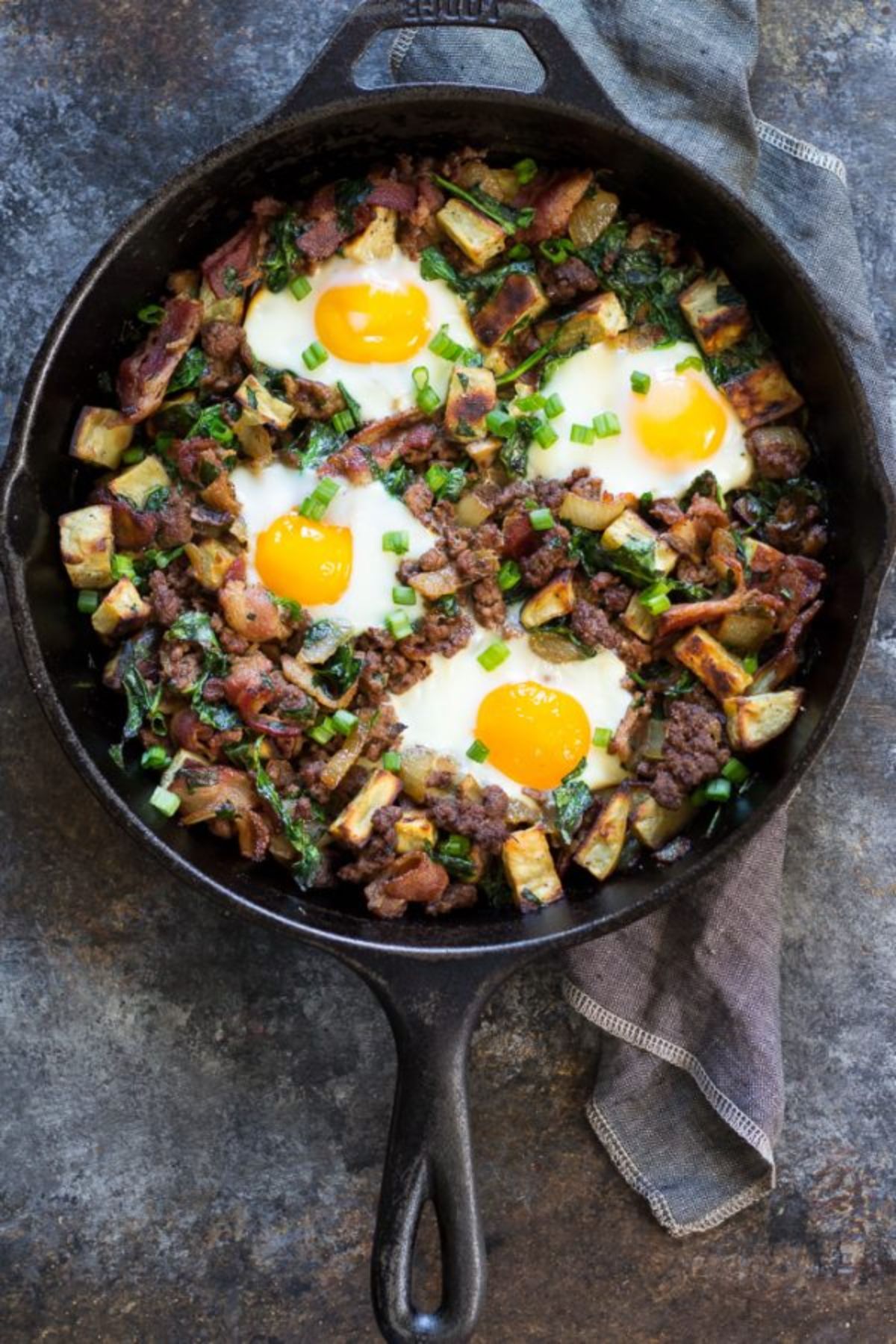 A cast iron skillet filled with beef casserole and topped with 4 fried eggs