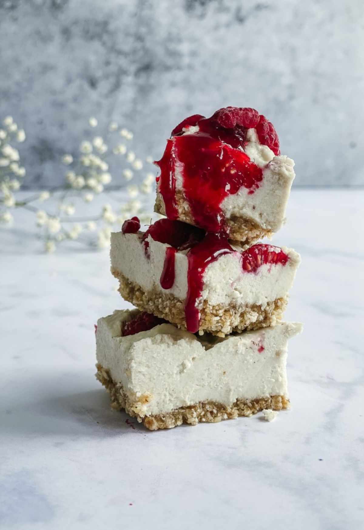 A pile of 3 vanilla cheesecake bites, topped with fruit coulis