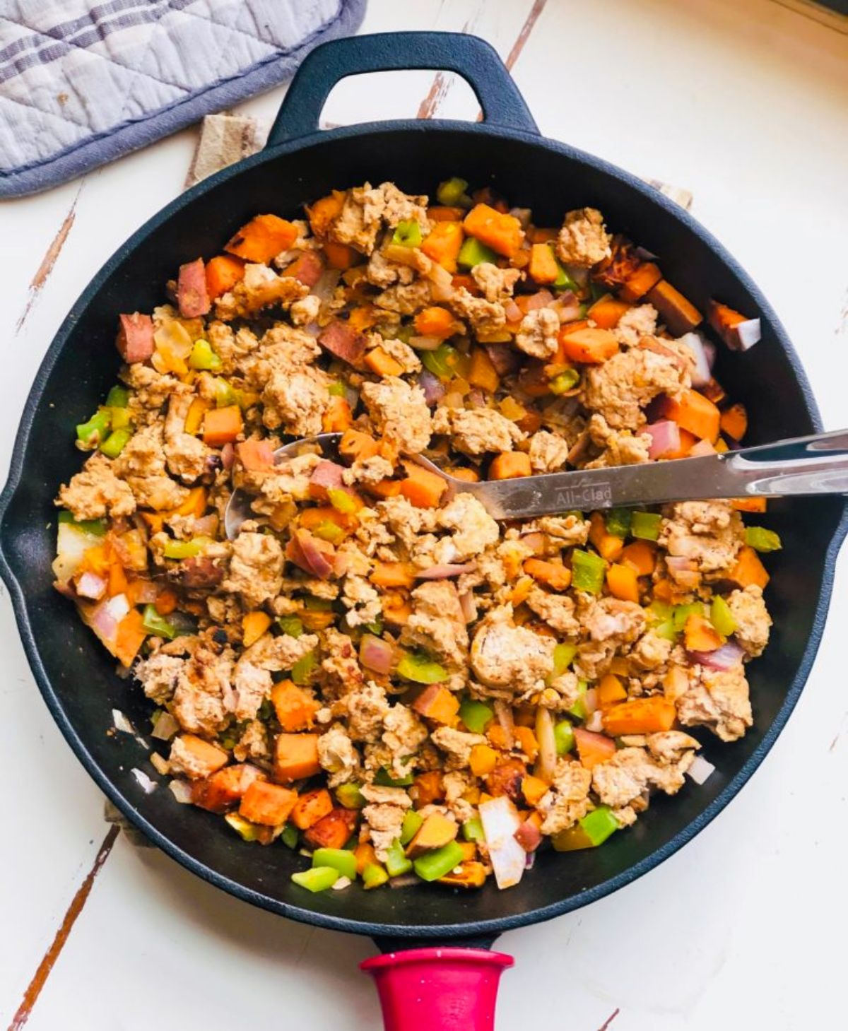 A cast iron skillet of ground turkey and vegetables with a spoon sticking out of it