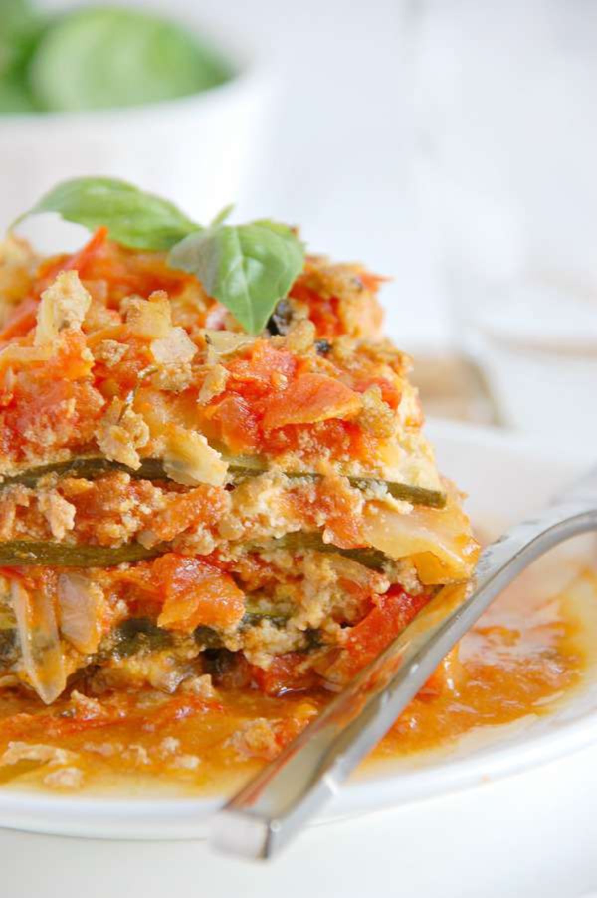 A partial shot of a plate with a portion of zucchini lasagne and a kinfe