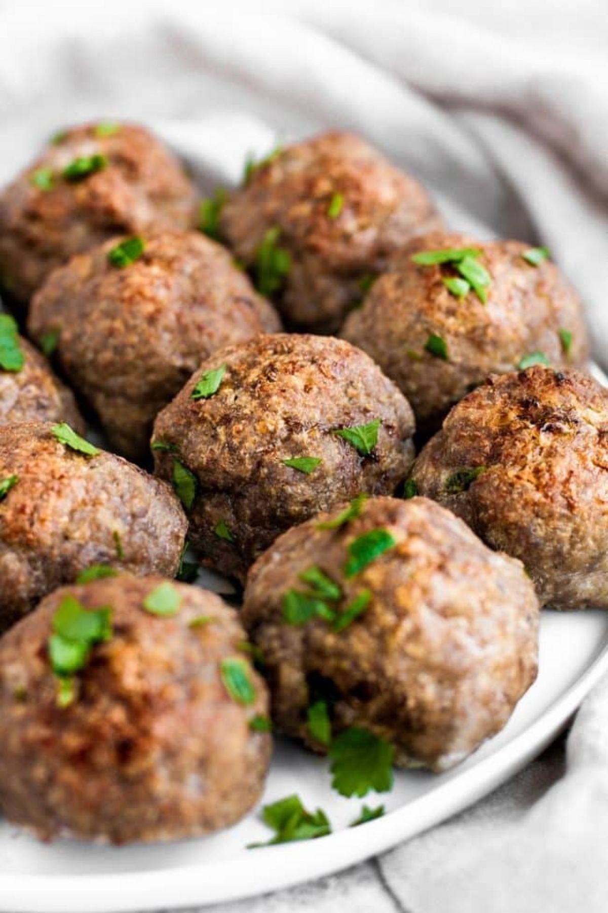 Meatballs on a white plate sprinkled with chopped herbs