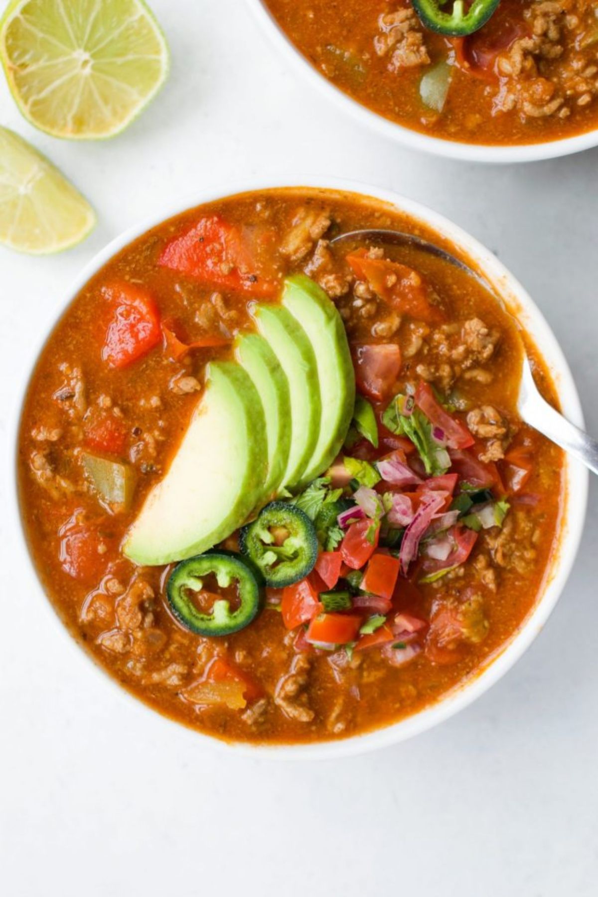 a bowl of taco soup topped with pear and chilli slices