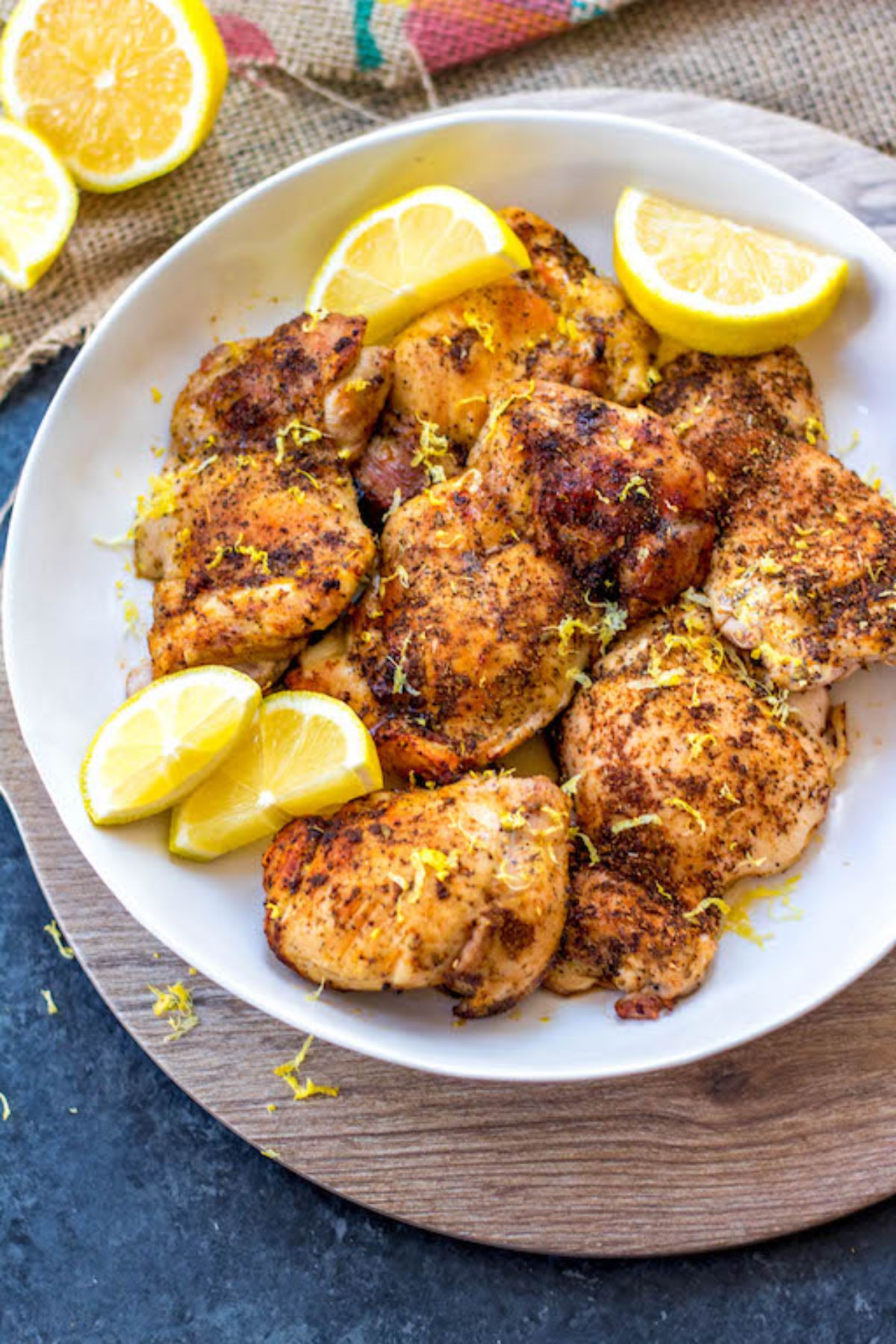 A plate of roast chicken thigsh with lemon zest and lemon slices