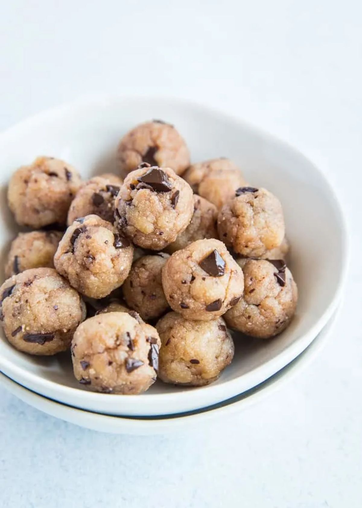 A white bowl with cookie dough balls in it