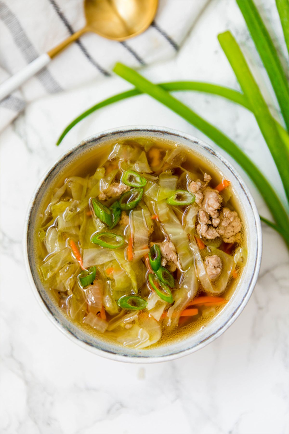 a bowl of ground beef and vegetable soup topped with sliced chillies