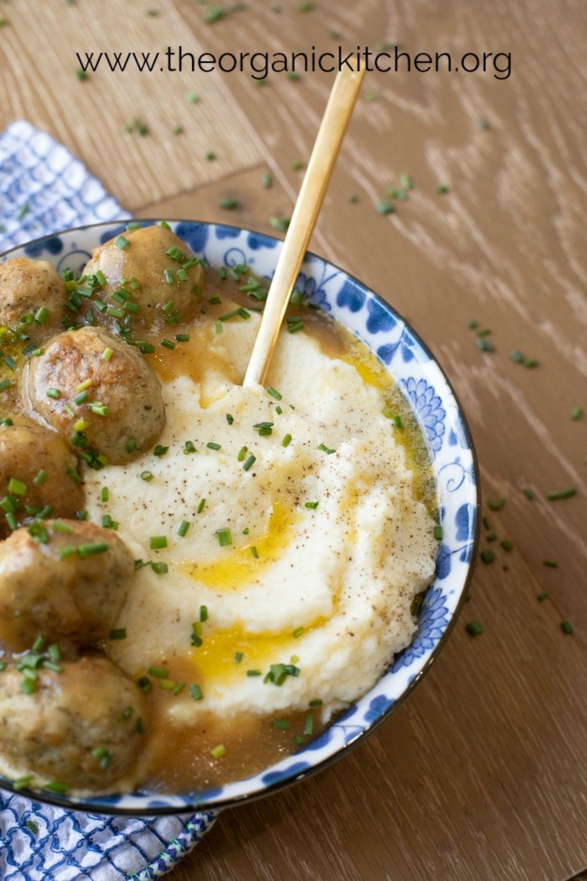A blue and white patterned bowl of meatballs in gravy with cauliflower mash
