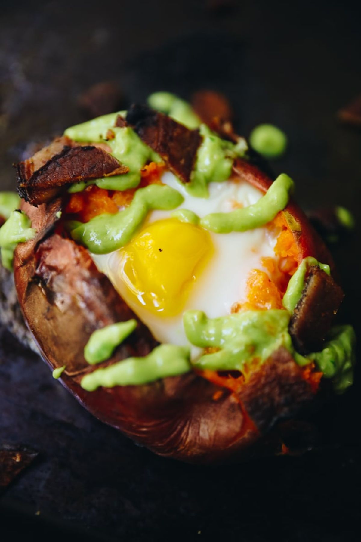 a sweet potato stuffed with a baked egg and drizzled with guacamole