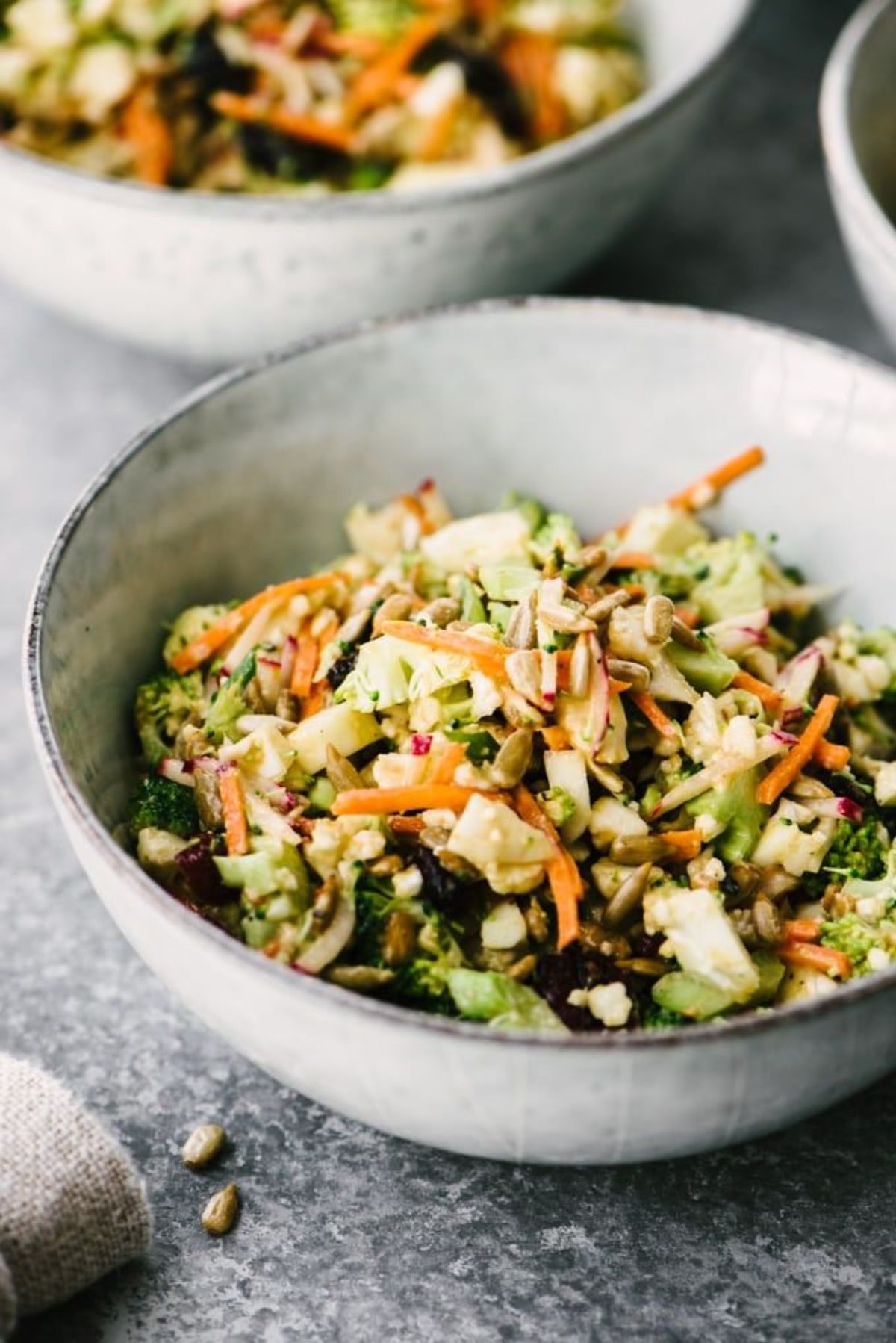 2 bowls of broccoli and cauliflower salad, sprinkled with sunflower seeds