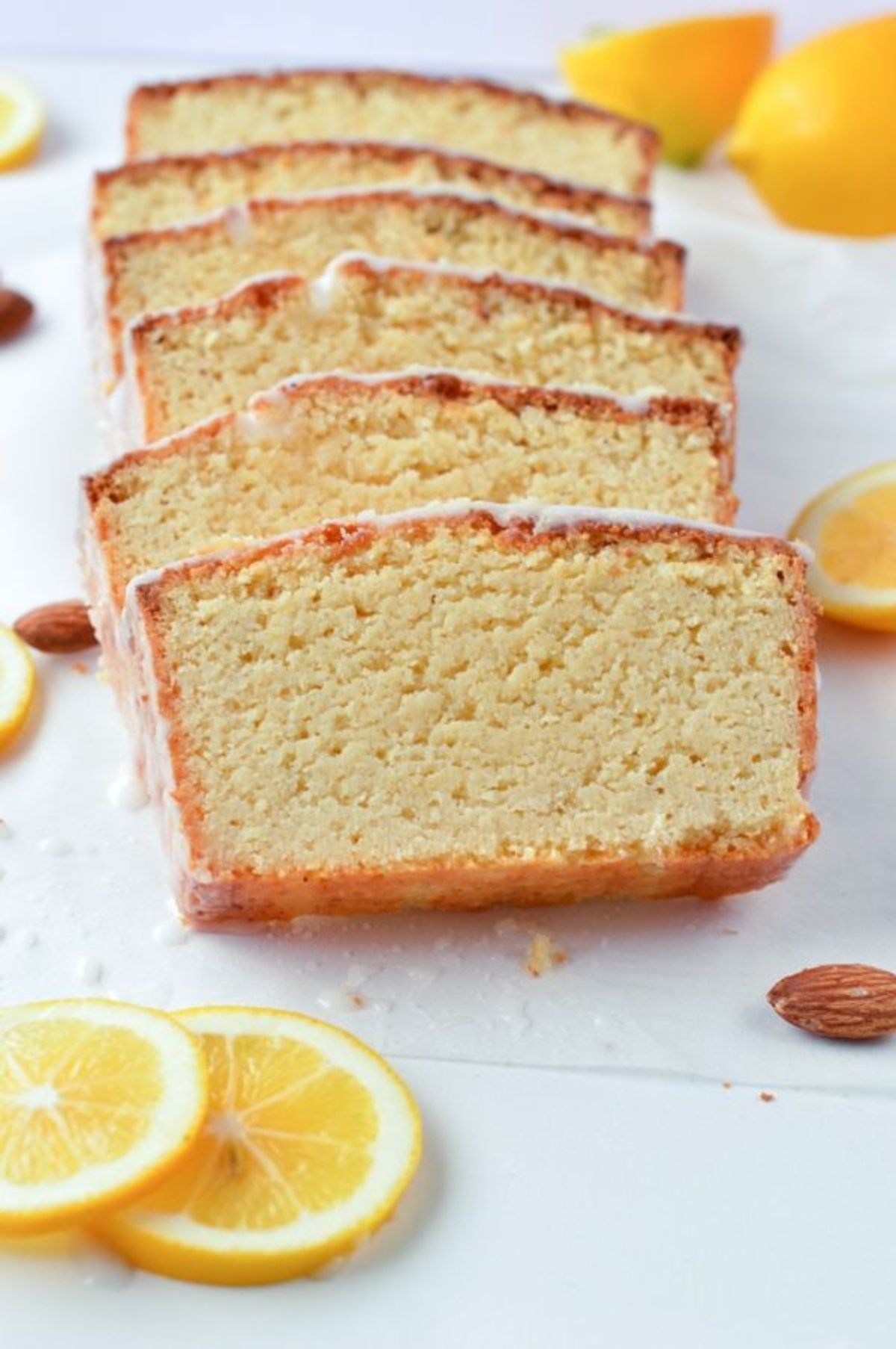 Slices of lemon cake with white icing. Lemon slices scattered around