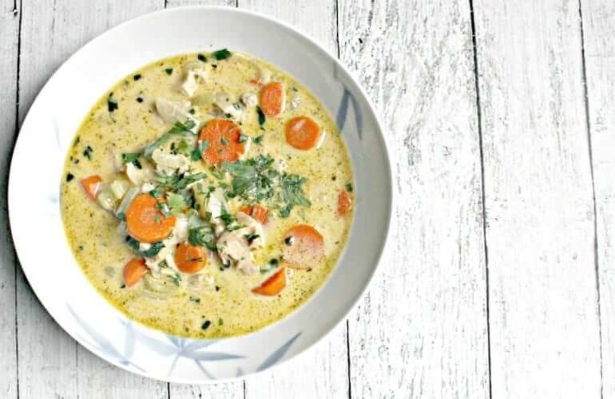 a white patterned bowl filled with creamy turkey and carrot soup