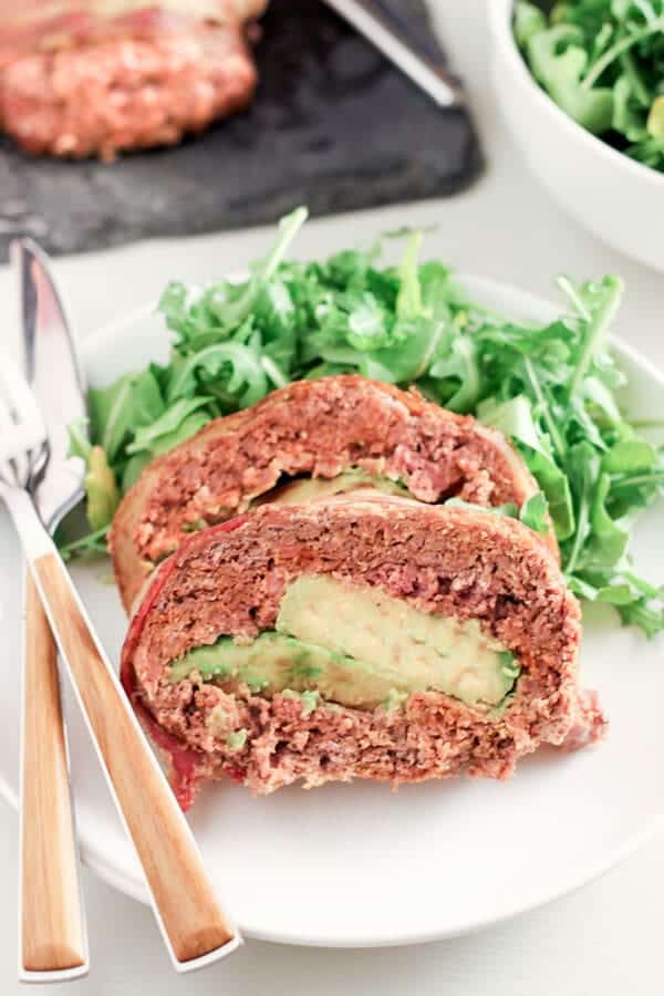 Close Up Shot Of Mexican Style Chorizo Meatloaf Stuffed With Avocado and Served With Green Salad on White Plate