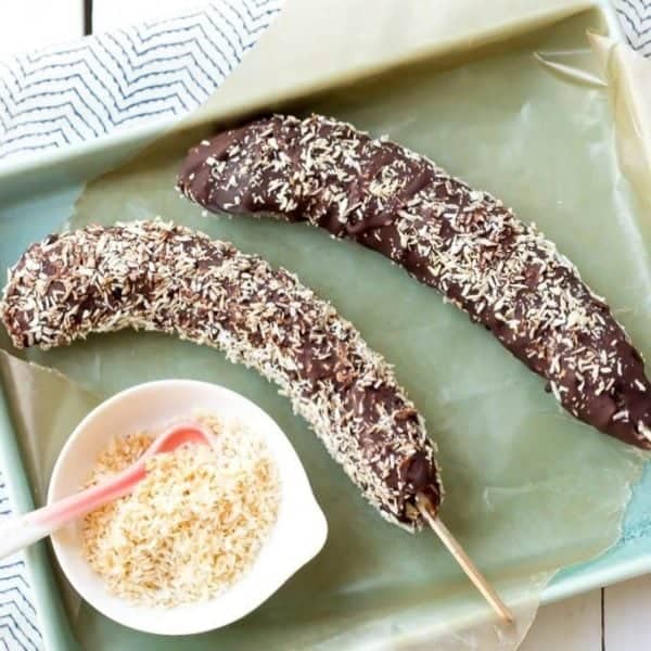 two frozen chocolate bananas with toasted coconut
