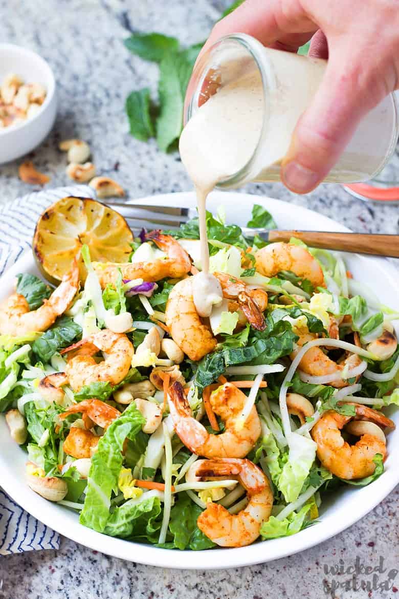 dressing being poured on thai salad