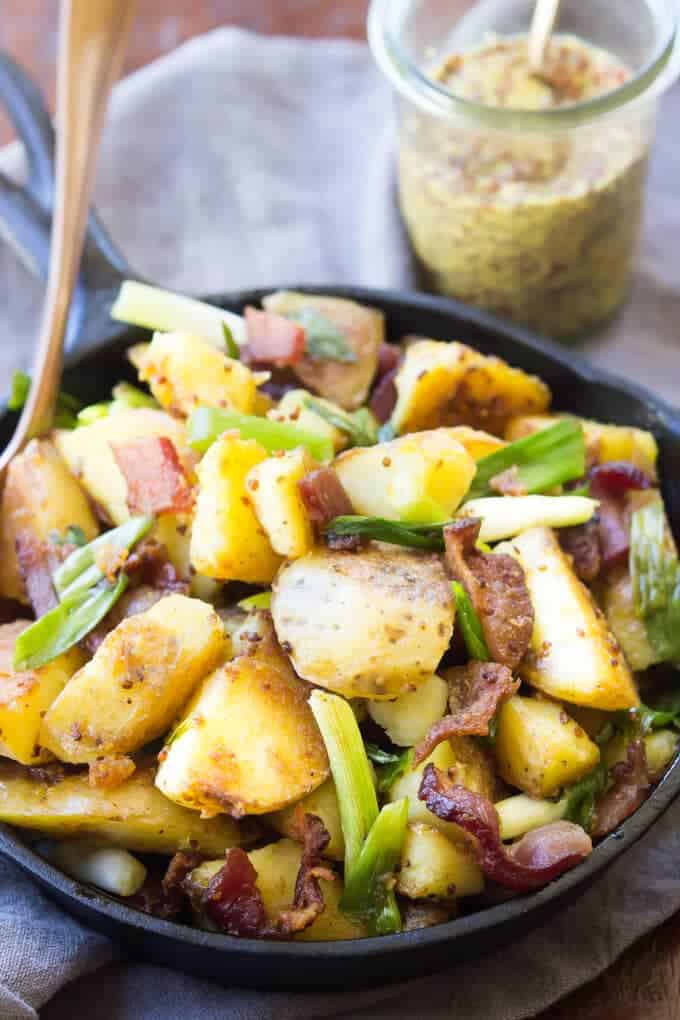 Overhead shot of German Fried Potatoes With Bacon And Onions With Jar Of Mustard