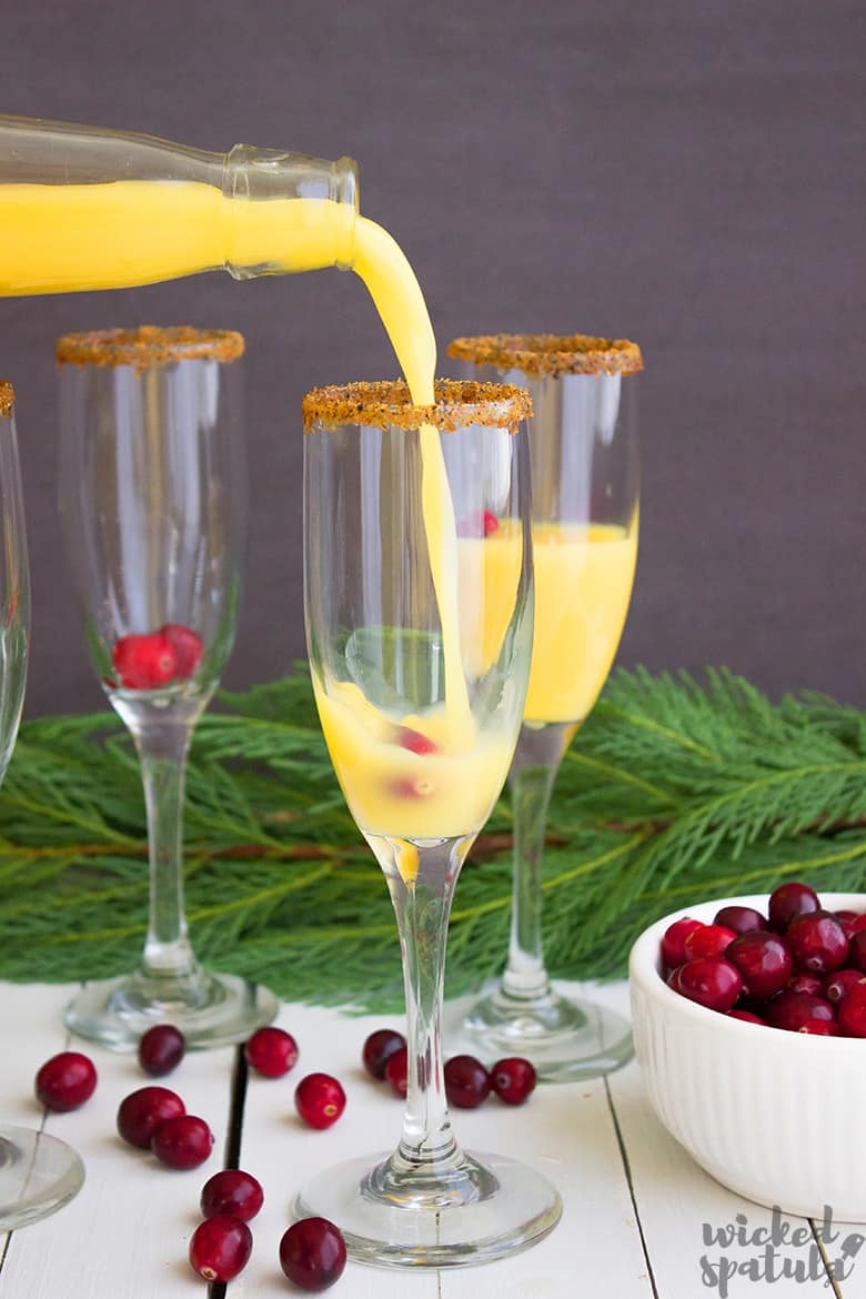 orange juice being poured into champagne glass