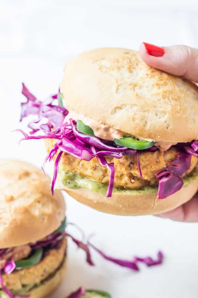 Side Shot Of Hand Holding Paleo Cauliflower Burger With Slaw