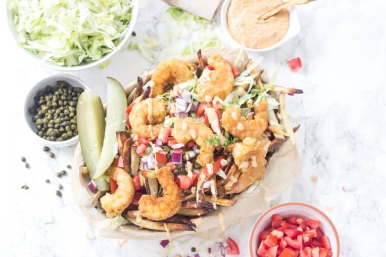 Shrimp Po'Boy FRIES!! These oven baked fries are topped with crispy fried shrimp, shredded lettuce, tomato, onion, capers, pickles, and a totally tasty remoulade sauce. Seriously, heaven on a plate! Gluten free and Paleo friendly!