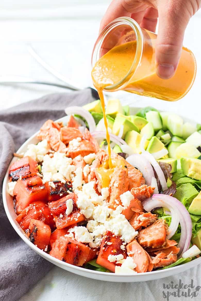 grilled salmon salad with dressing pouring 