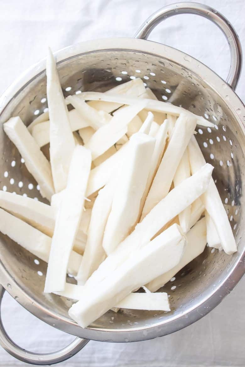 Overhead shot of raw yuca fries in colander