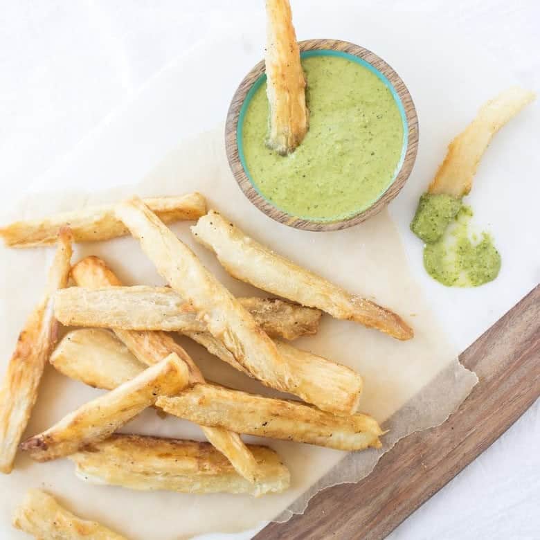 Yuca Fries on board served with green sauce in a bowl