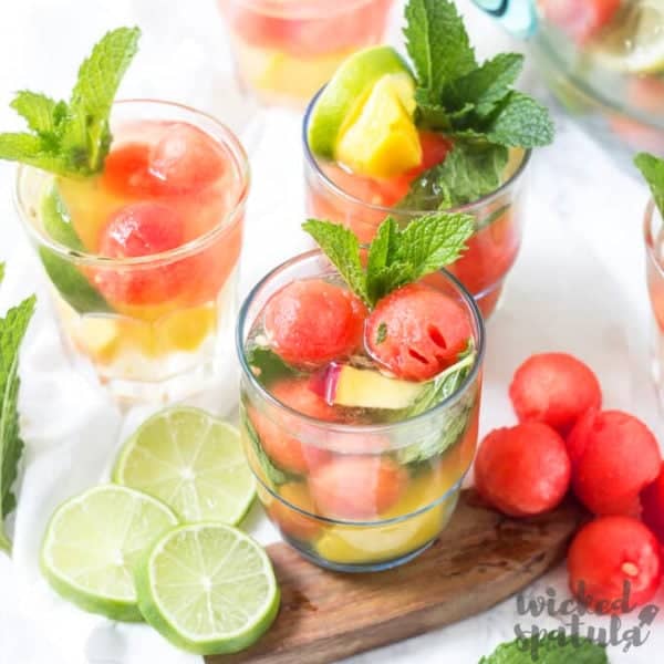 summer white sangria in glasses with melon balls and mint garnish