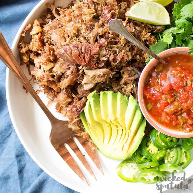 slow cooker carnitas on platter with avocado and salsa