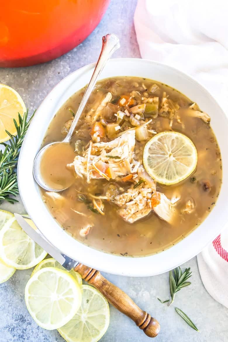 Overhead shot of bowl of soup with chicken and lemon with lemons scattered around.