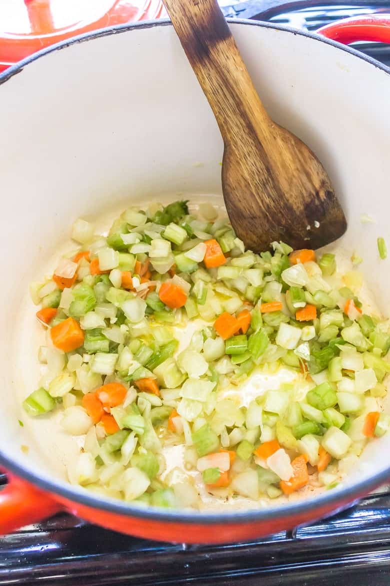 Overhead shot of Mirepoix (mixture of carrots, onions and celery) being sautéed in olive oil as the starting base for a soup.