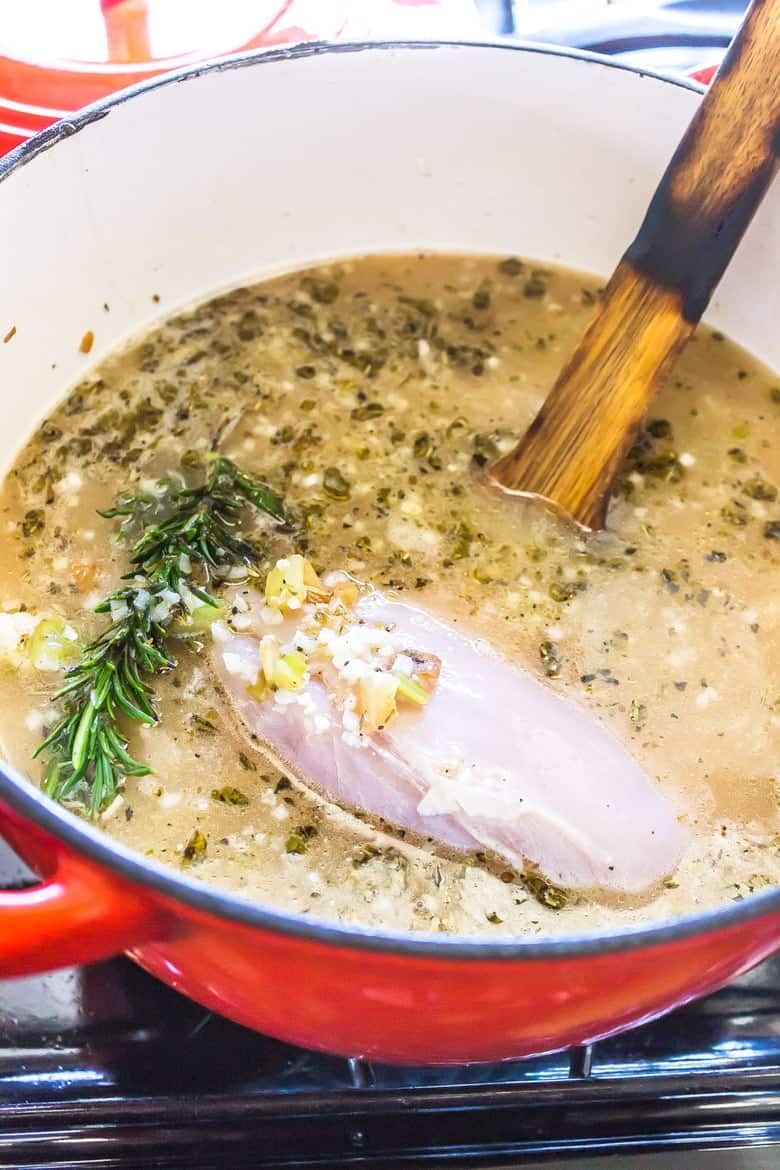 Overhead Shot Of Dutch Oven Pan With Soup Ingredients Including Uncooked Chicken