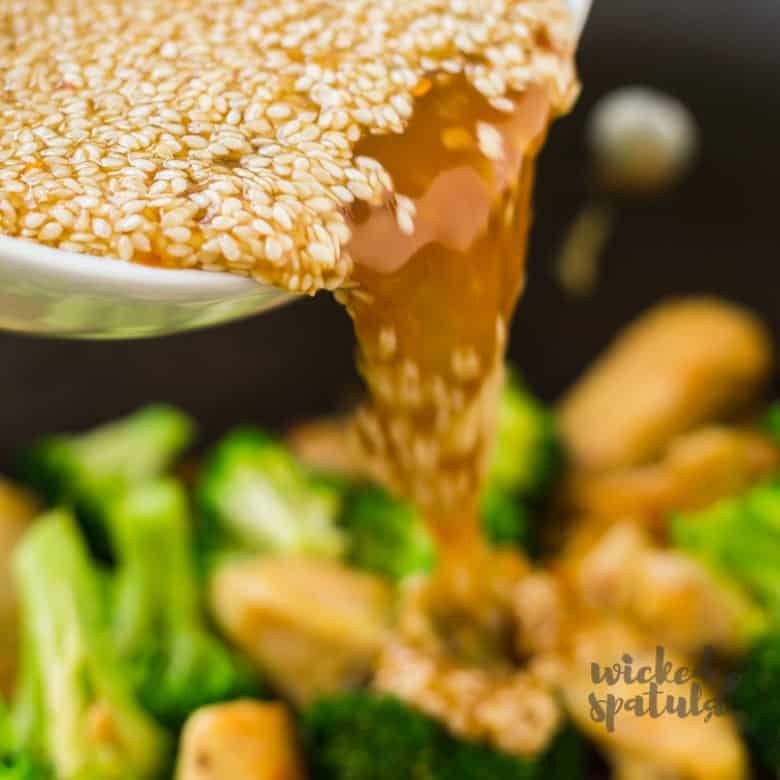 Pouring sesame chicken sauce over sesame chicken