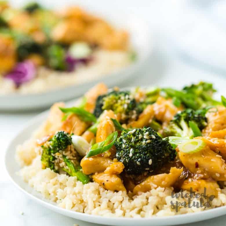 Side view of sesame chicken on plate with cauliflower rice