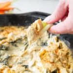 scooping paleo spinach artichoke dip with celery