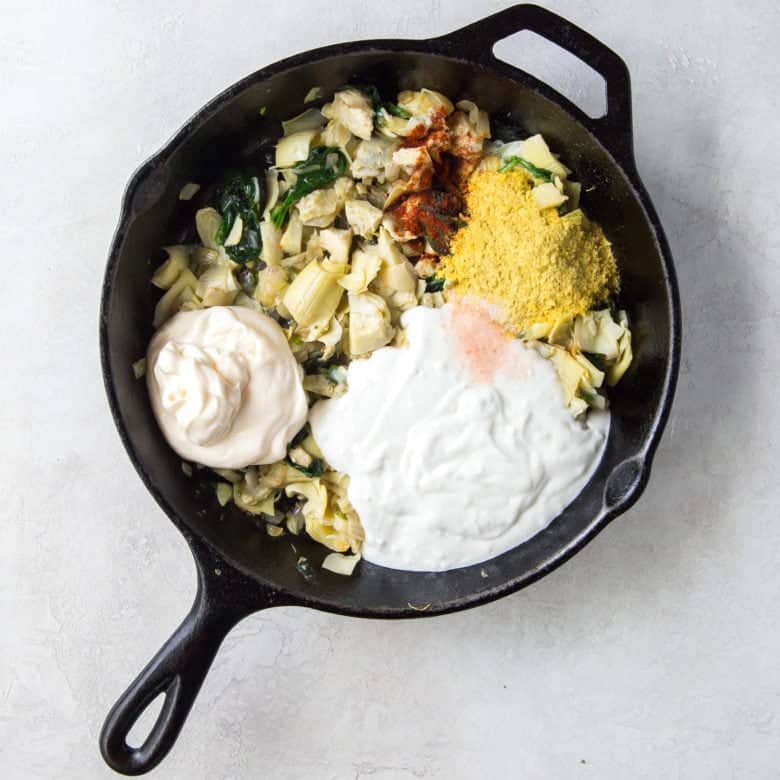 ingredients for vegan spinach artichoke dip in a skillet