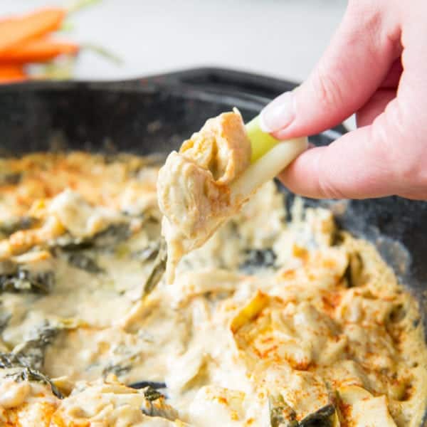 celery scooping up paleo spinach artichoke dip