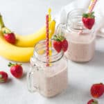 strawberry and banana smoothie with fruit in the background
