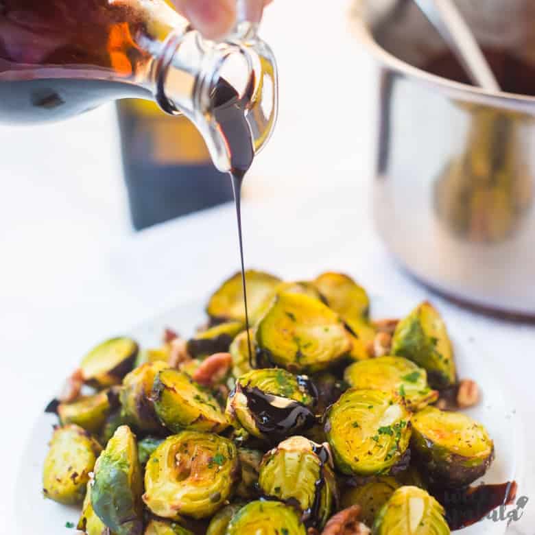 pouring balsamic glaze out of glass container on veggies