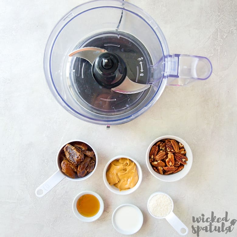 paleo no bake energy balls ingredients in bowls next to a blender