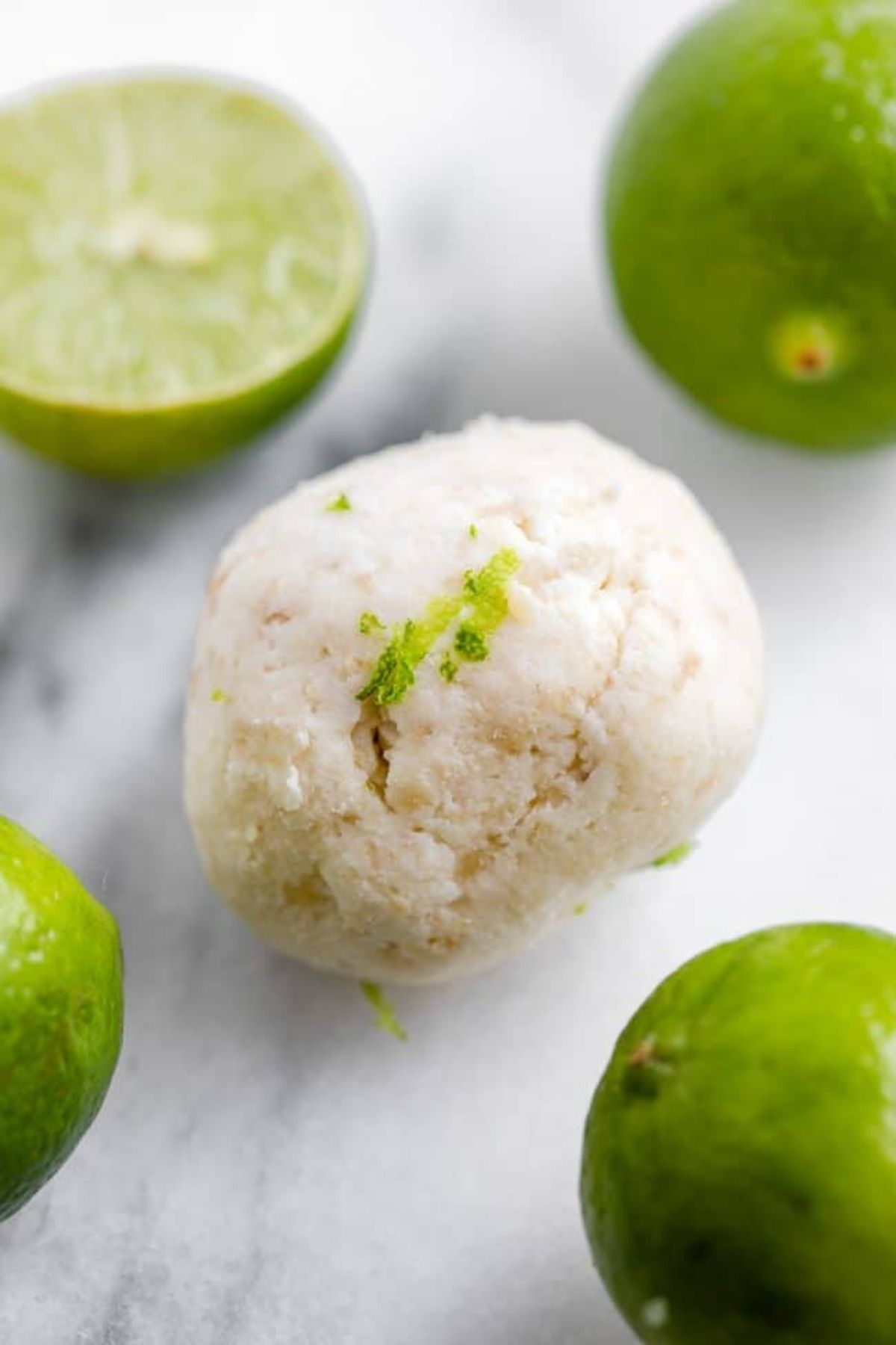 A bal of key lime pie dough surrounded with limes