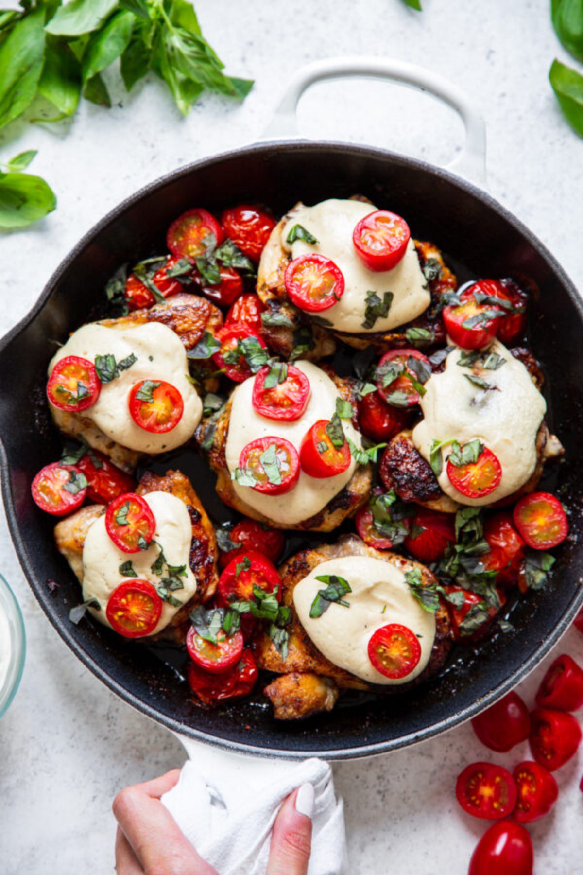 a skillet full of chicken thighs topped with cheese and tomatoes