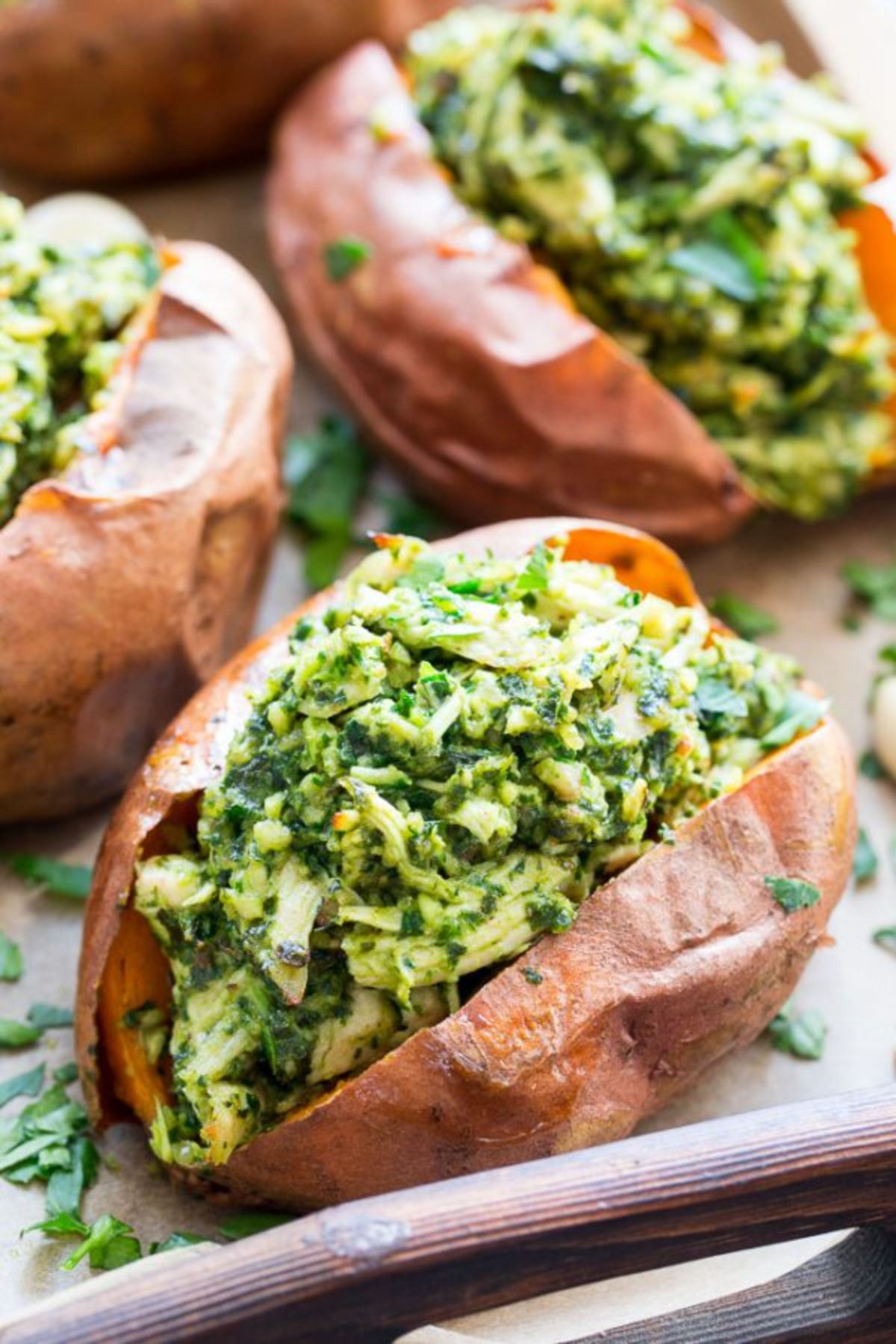 a baking tray with baked sweet potatoes stuffed with pesto chicken