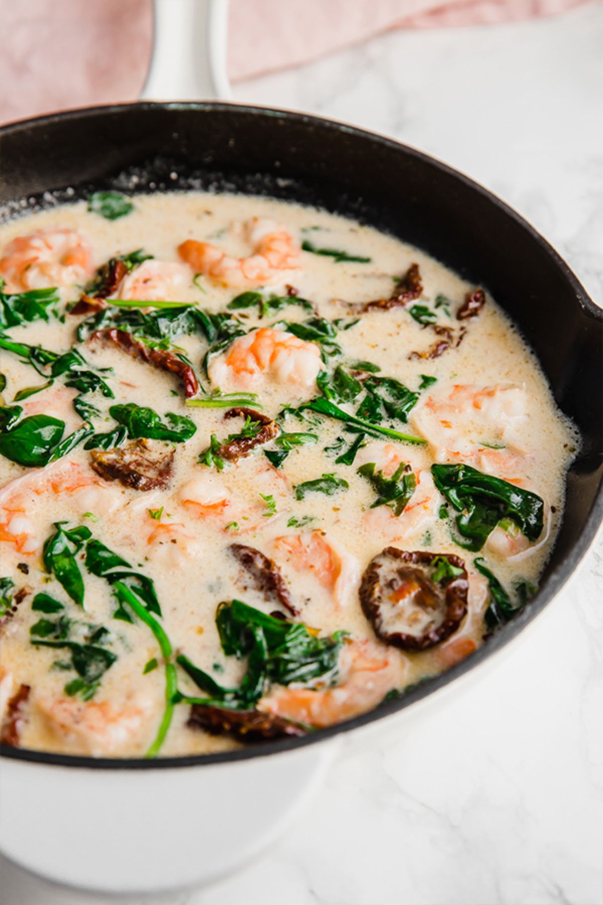 a cast iron skillet with shrimp and mushrooms in creamy sauce