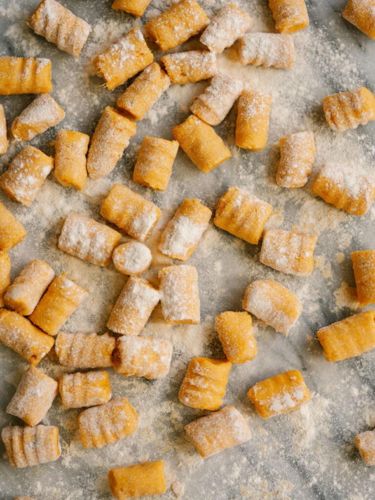 a baking tray with uncooked potato gnocchi, sprinkled with flour