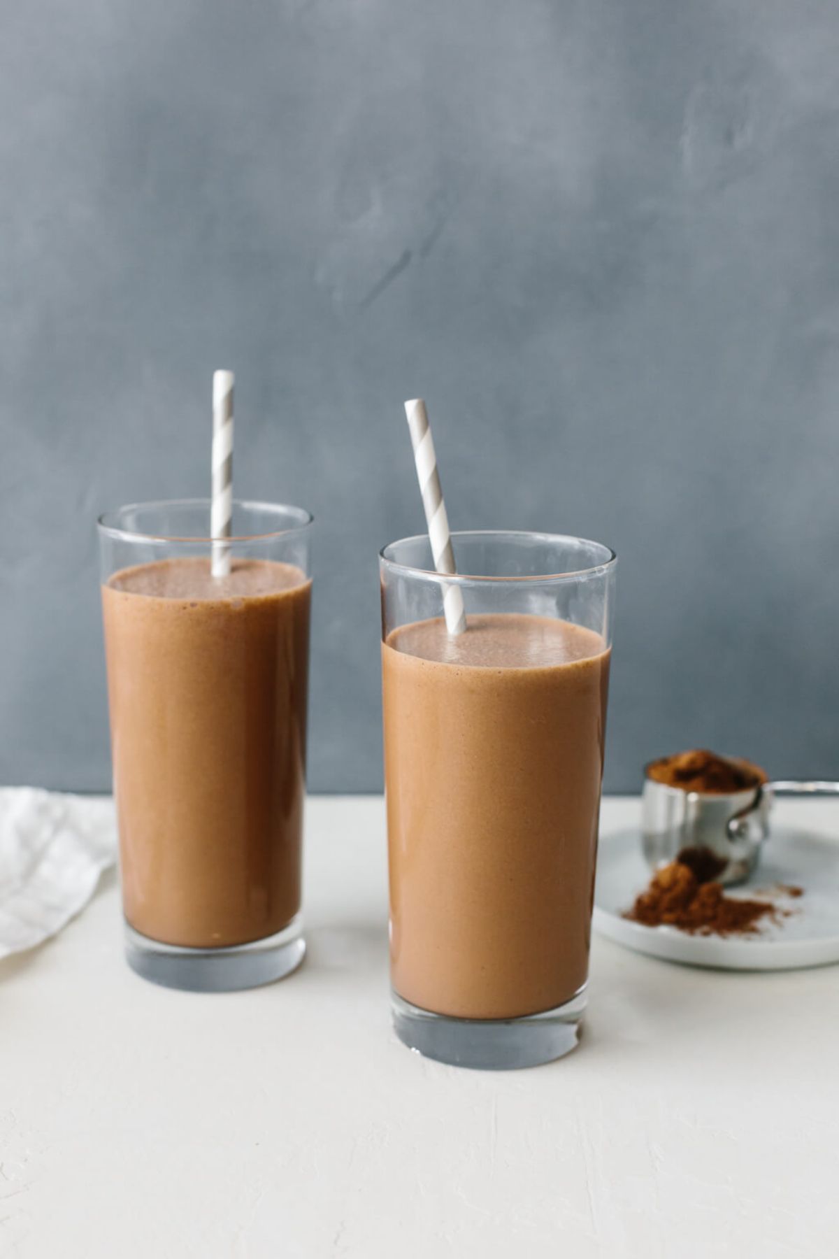 2 glasses of chocolate smoothie with straws sticking out