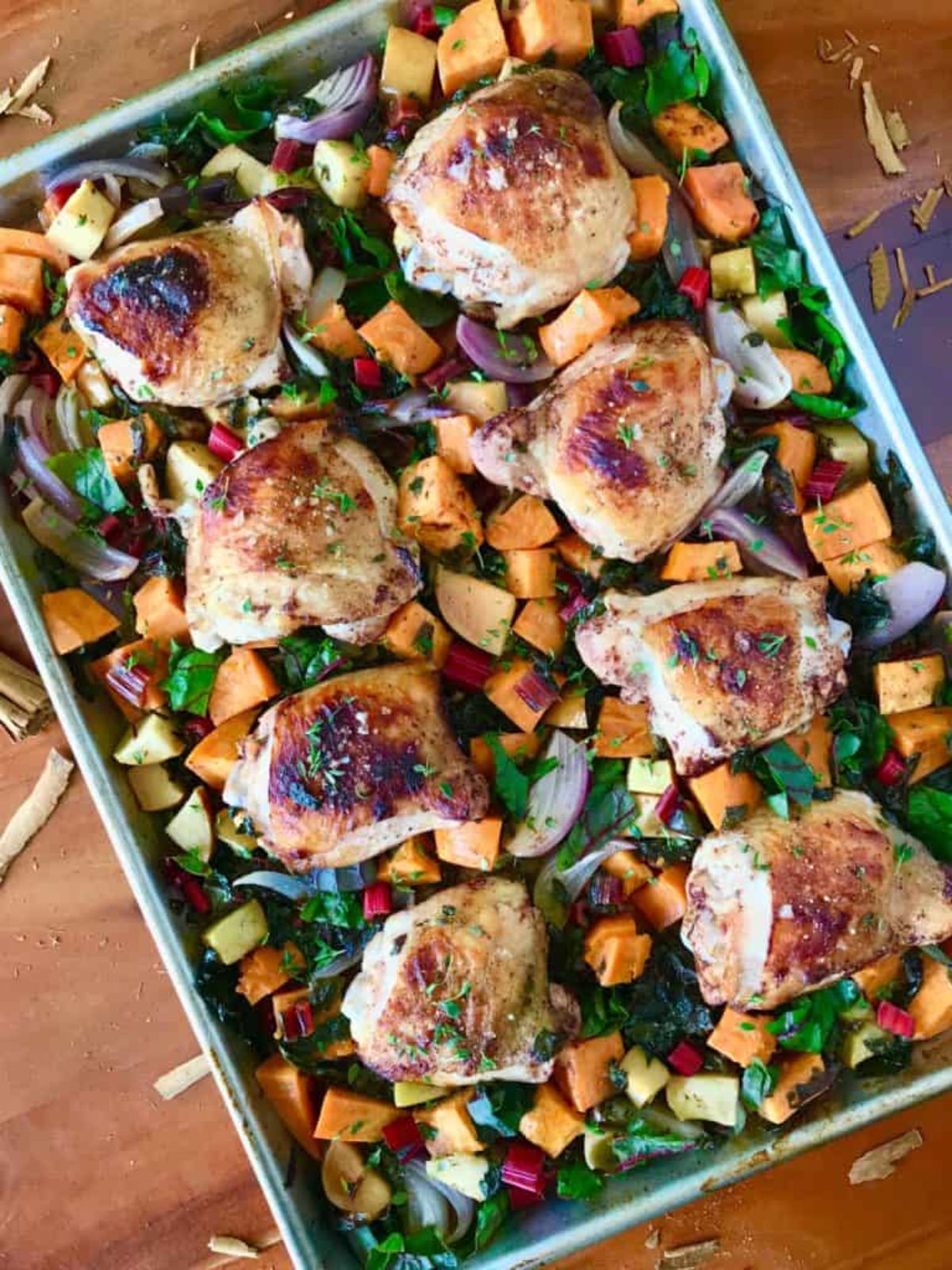 a large sheet pan with chicken thighs on a bed of chopped vegetables