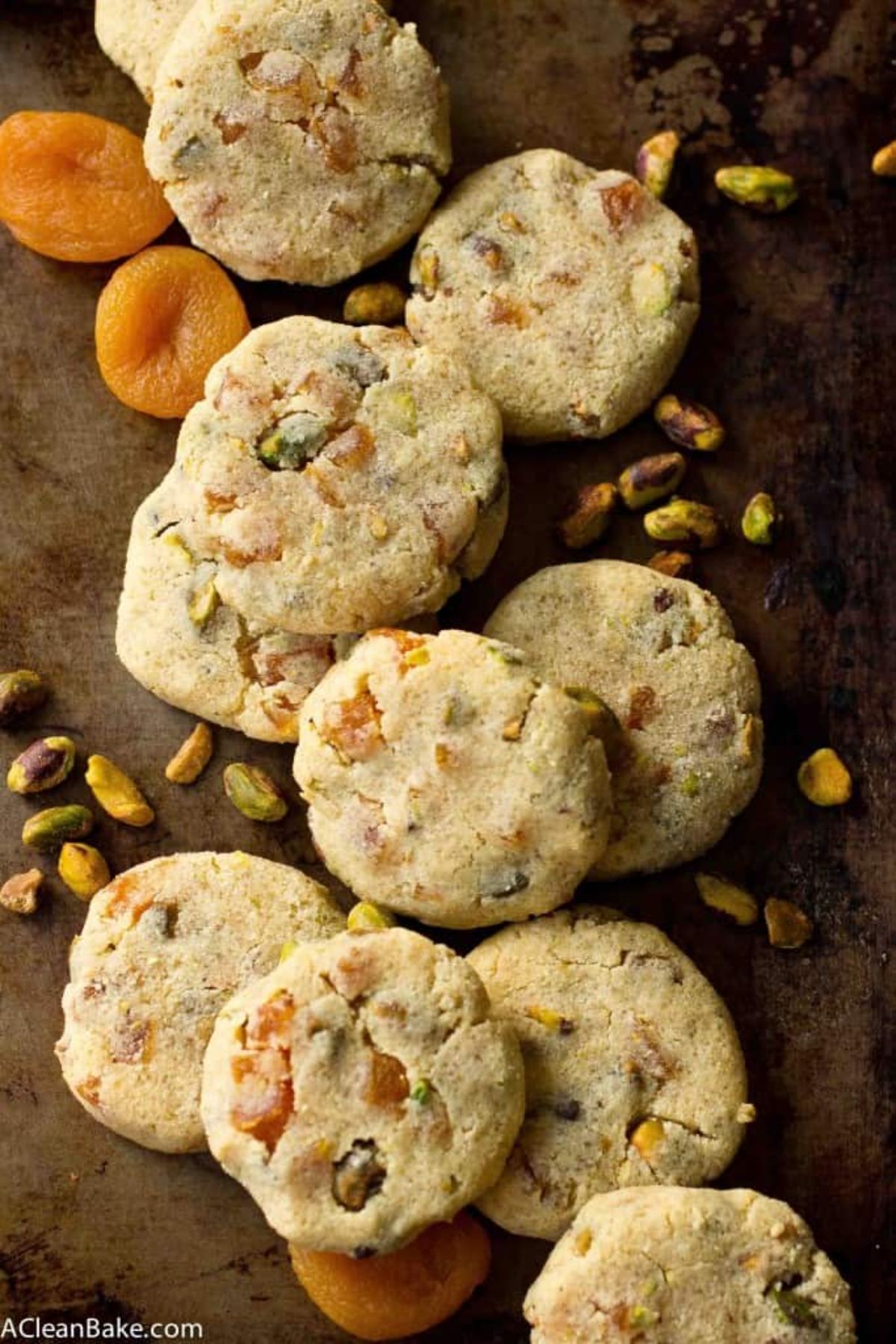 a pile of aprocot and pistachio biscuits with dried nuts and fruit scattered over them