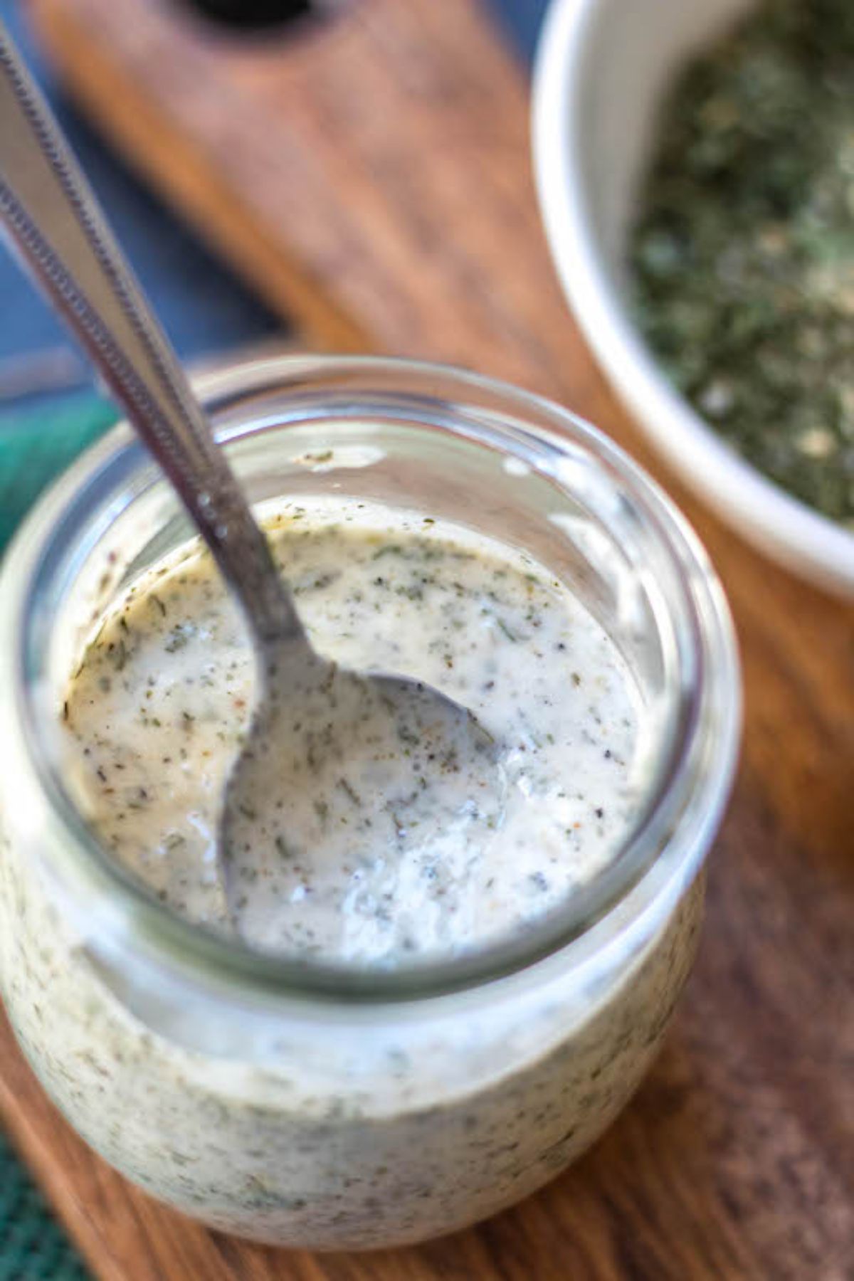 A glass jar with white, creamy sauce and a spoon resting in it