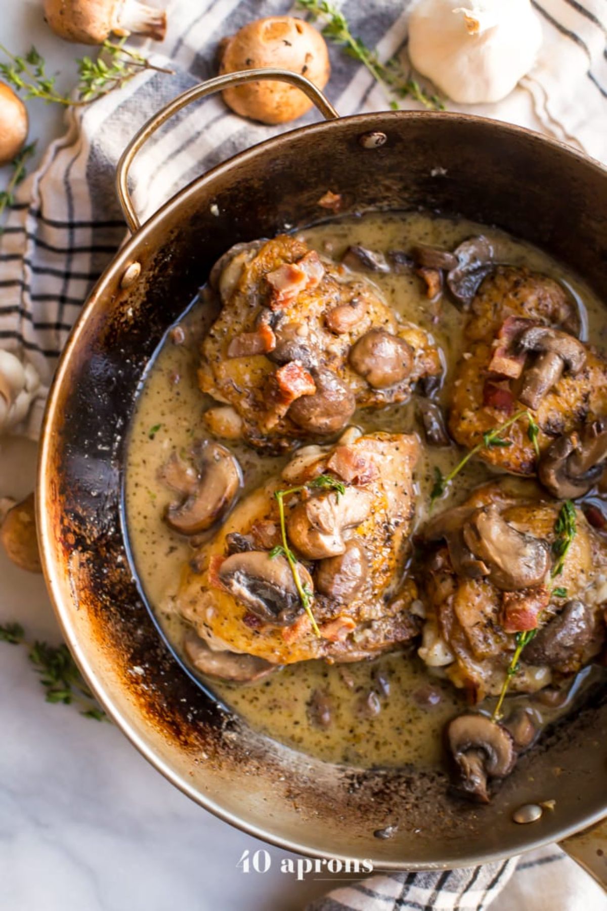 a skillet with chicken thighs in a mushroom and bacon sauce